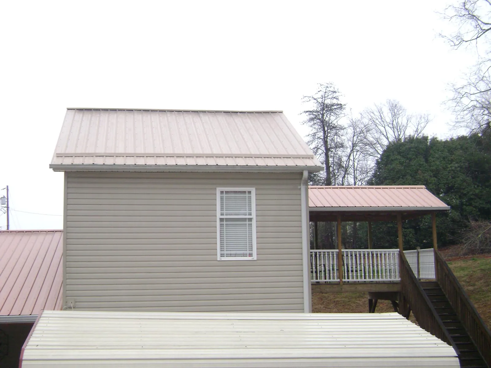 Tan metal roofs on a two story addition and attached porch, from a Roof Replacement job in Powder Springs
